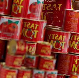 一堆装满番茄酱的可口汤姆罐头, Olam also manufactures pasta, biscuits, 为非洲市场提供酸奶饮料和食用油.